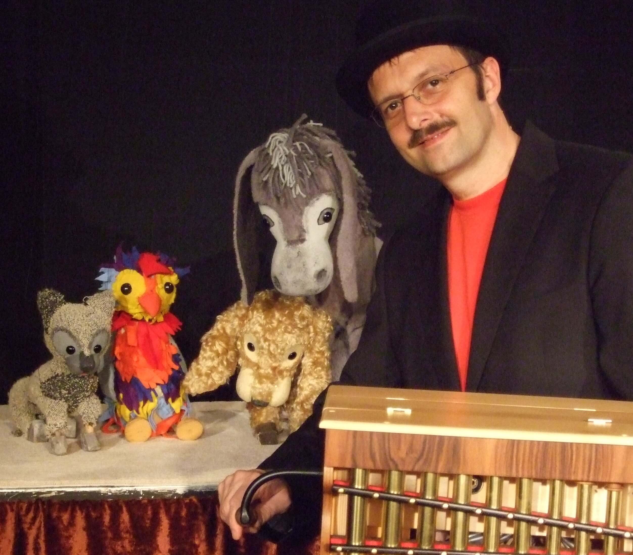 Foto: Foto der Marionetten mit dem Puppenspiler Wolfgang Kaup-Wellfonder, der eine Drehorgel bedient