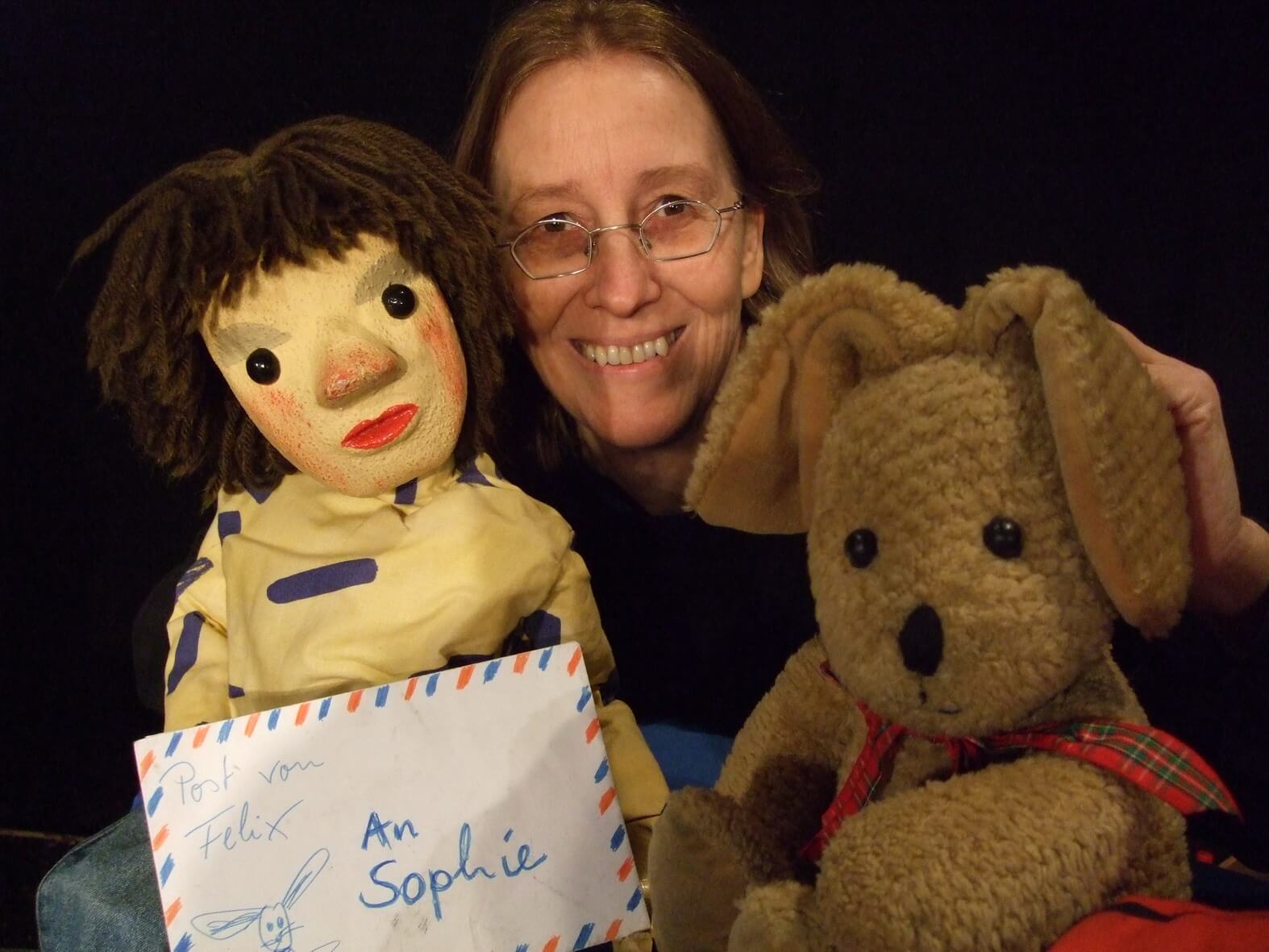 Foto: Marionette Sophie mit Brief in der Hand, Puppenspielerin Dorothee Wellfonder und der Kuschelhase Felix