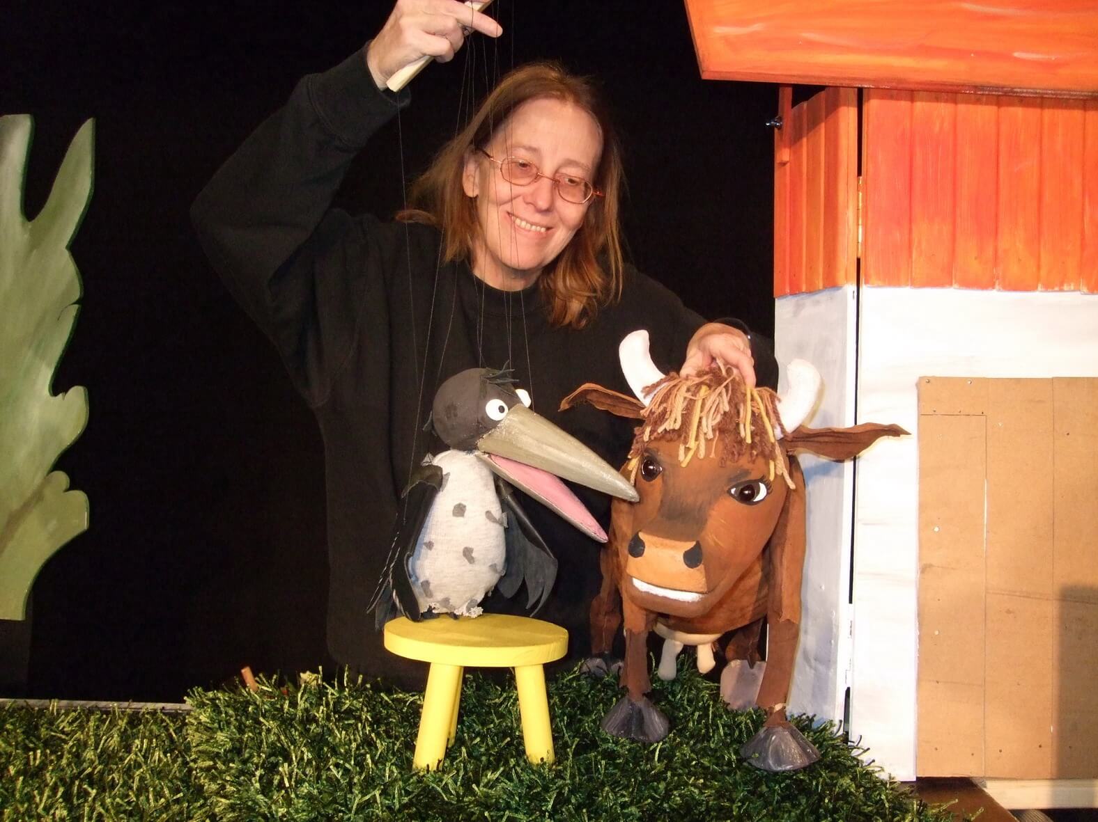Foto aus der Vorstellung: Puppenspielerin Doro Wellfonder spielt die Marionette von der Krähe und Figur von der Kuh